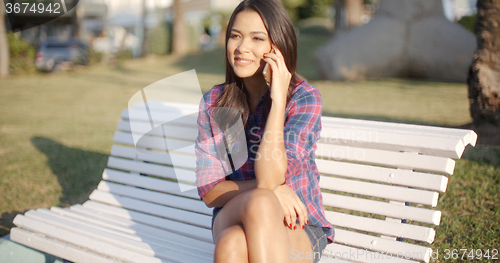Image of Woman Using Cell Phone On Park Bench