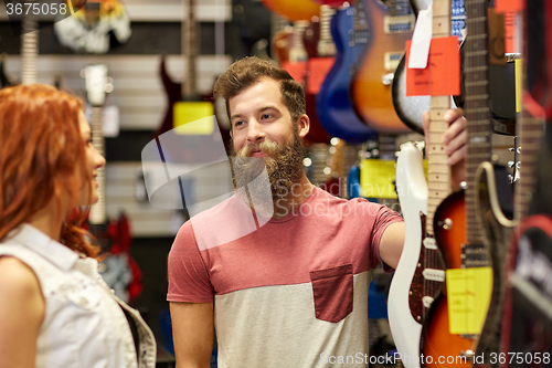 Image of couple of musicians with guitar at music store