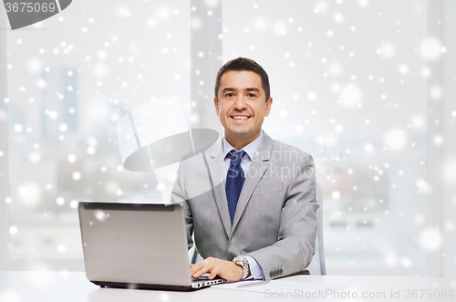 Image of smiling businessman with laptop and papers