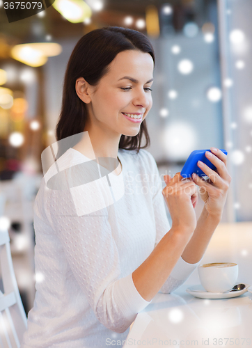 Image of smiling woman with smartphone and coffee at cafe
