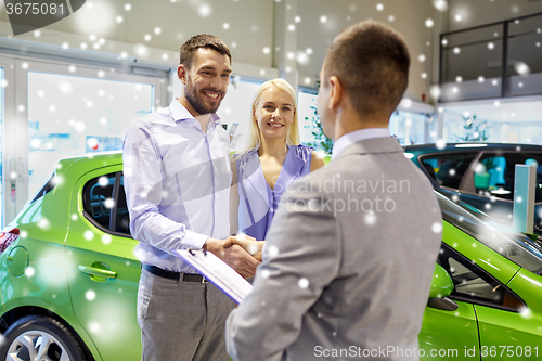 Image of happy couple with car dealer in auto show or salon