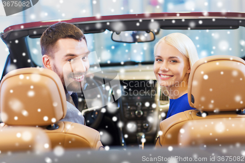 Image of happy couple sitting in car at auto show or salon