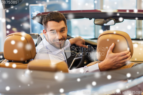 Image of man sitting in cabriolet car at auto show or salon