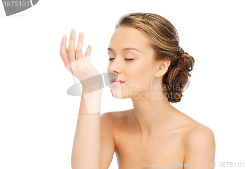 Image of woman smelling perfume from wrist of her hand