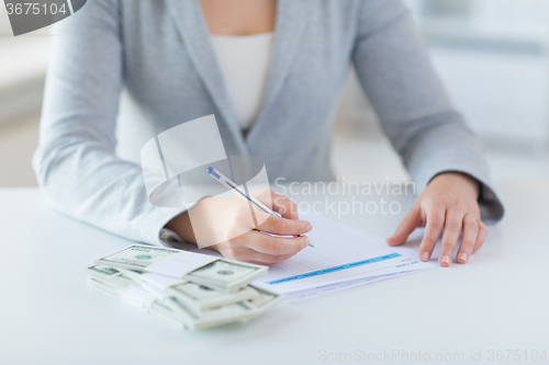 Image of close up of hands with money filling tax form