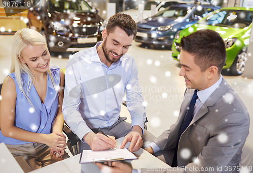 Image of happy couple with car dealer in auto show or salon