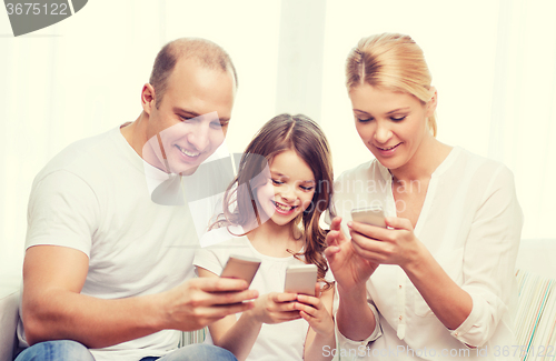 Image of parents and little girl with smartphones at home