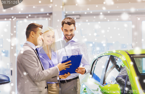 Image of happy couple with car dealer in auto show or salon
