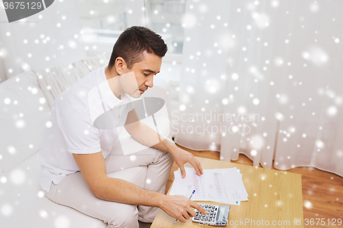 Image of man with papers and calculator at home