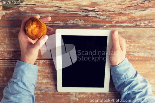 Image of close up of male hands with tablet pc and muffin