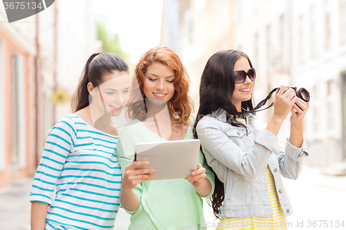 Image of smiling teenage girls with tablet pc and camera