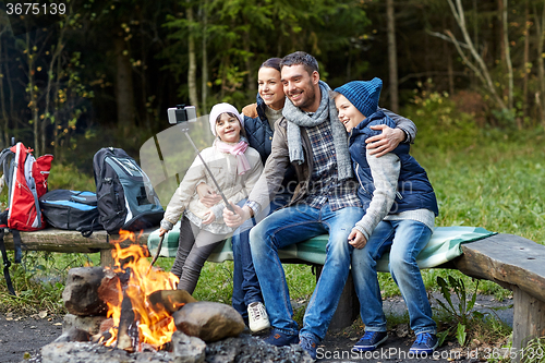 Image of family with smartphone taking selfie near campfire