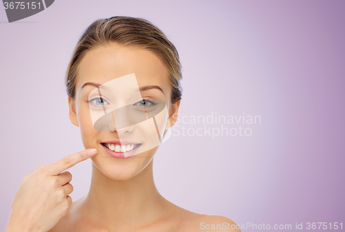 Image of happy young woman pointing finger to her smile