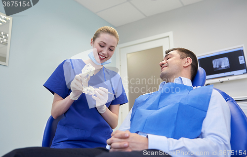 Image of happy dentist showing jaw layout to male patient