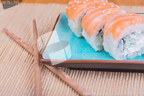 Image of California maki sushi with fish and chopsticks