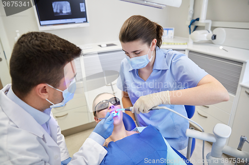 Image of dentists treating male patient teeth at clinic