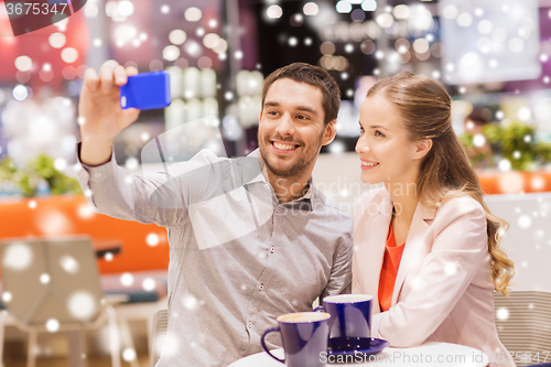 Image of happy couple with smartphone taking selfie in mall