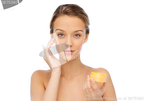 Image of young woman appying cream to her face