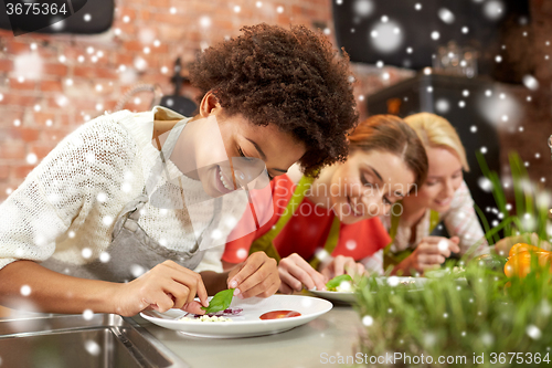 Image of happy women cooking and decorating dishes