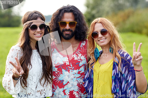 Image of happy young hippie friends showing peace outdoors