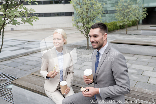 Image of smiling businessmen with paper cups outdoors