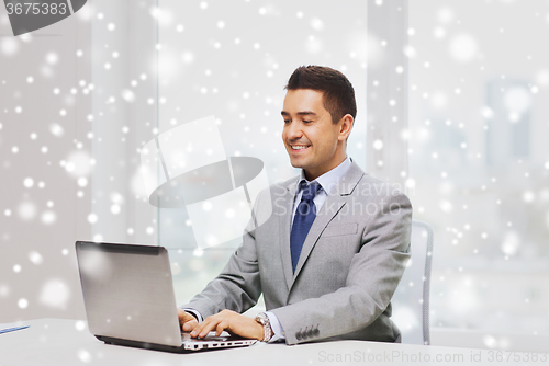 Image of happy businessman working with laptop in office