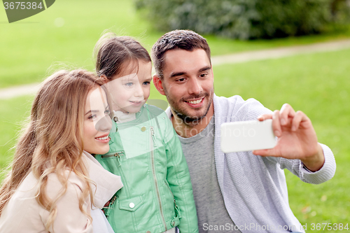 Image of happy family taking selfie by smartphone outdoors