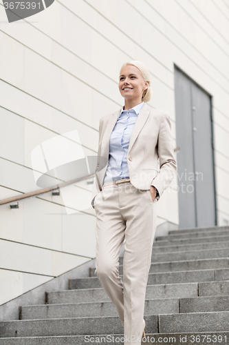 Image of young smiling businesswoman walking down stairs