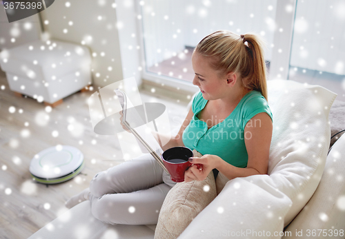 Image of happy woman reading magazine with tea cup at home