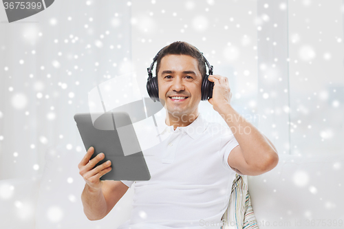 Image of smiling man with tablet pc and headphones at home