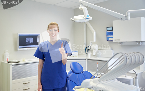 Image of happy female dentist showing thumbs up at clinic
