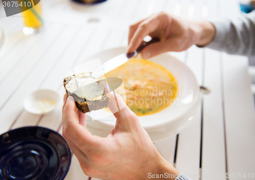 Image of close up of hands applying butter to bread