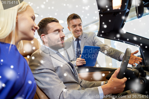 Image of happy couple with car dealer in auto show or salon