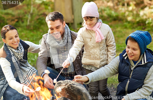 Image of happy family roasting marshmallow over campfire