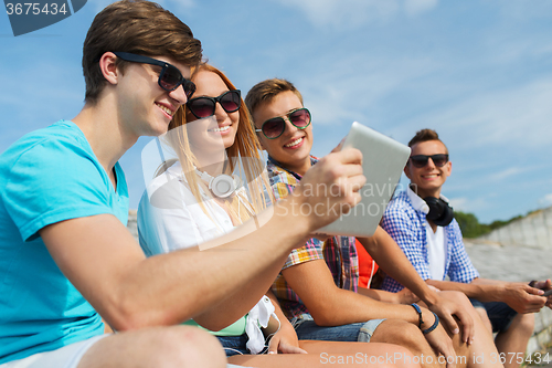 Image of group of smiling friends with tablet pc outdoors