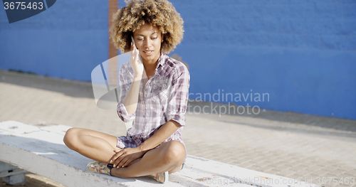 Image of Woman With Smartphone Sitting On Stone Wall