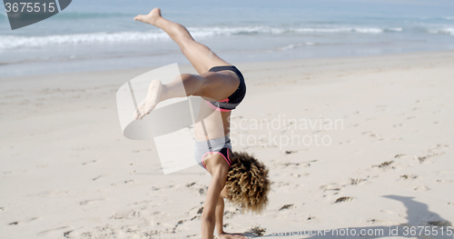 Image of Young Woman Doing Cartwheel On Beach