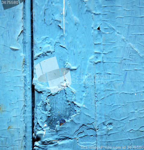 Image of dirty stripped paint in the blue wood door and rusty nail