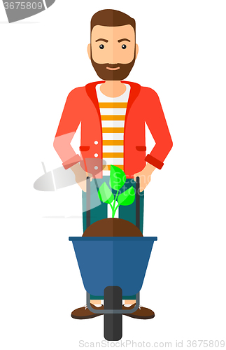 Image of Man with plant and wheelbarrow.