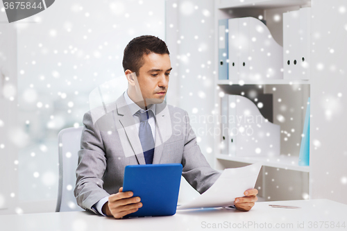 Image of businessman with tablet pc and papers in office