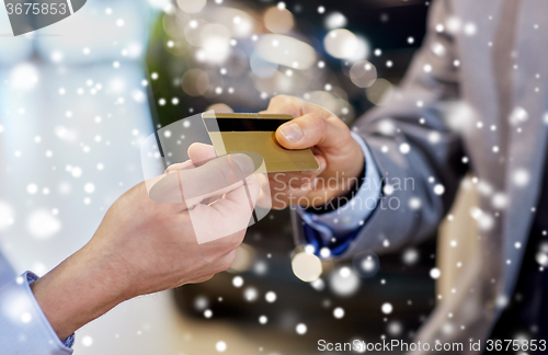 Image of customer giving credit card to car dealer in salon