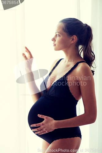 Image of happy pregnant woman with big bare tummy at home