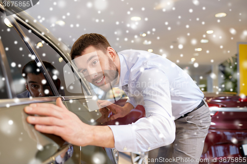 Image of happy man touching car in auto show or salon