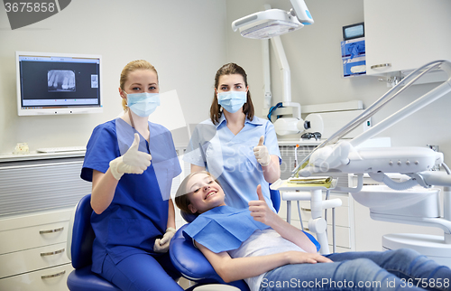 Image of happy female dentist with patient girl at clinic