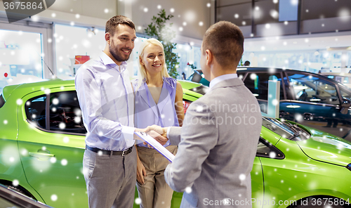 Image of happy couple with car dealer in auto show or salon