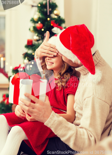 Image of smiling father surprises daughter with gift box