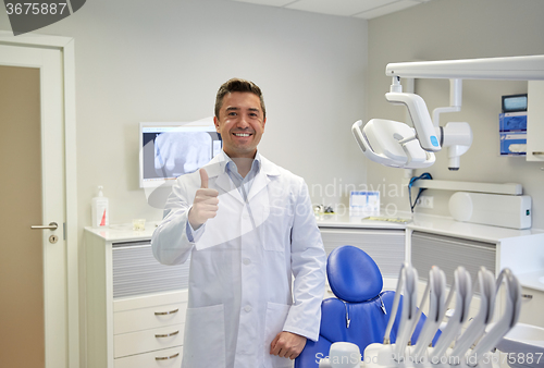 Image of happy male dentist showing thumbs up at clinic