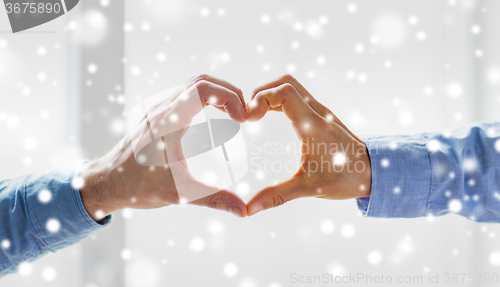 Image of close up of male gay couple hands showing heart