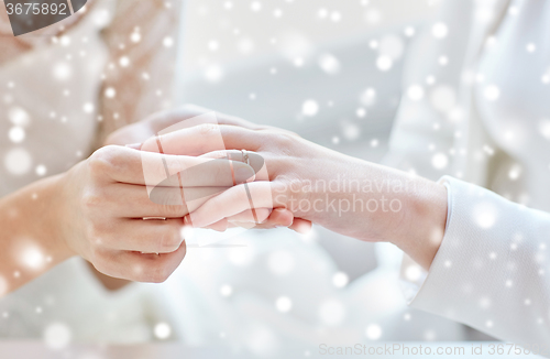 Image of close up of lesbian couple hands with wedding ring