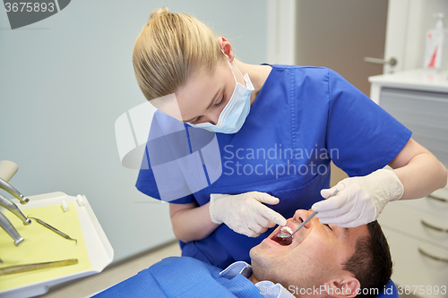 Image of female dentist checking up male patient teeth